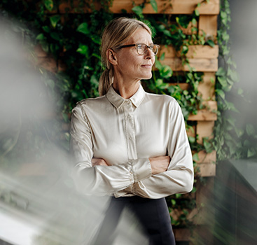 Female office worker pensive with greenery behind her