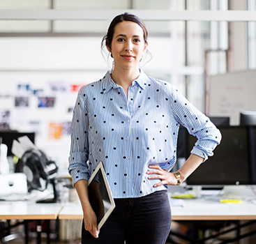Female office worker holding notebook in open plan office