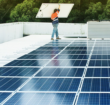 Worker installing solar panels to building rooftop